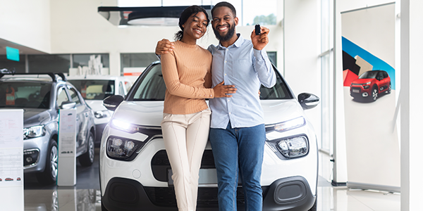 A couple standing in front of their car